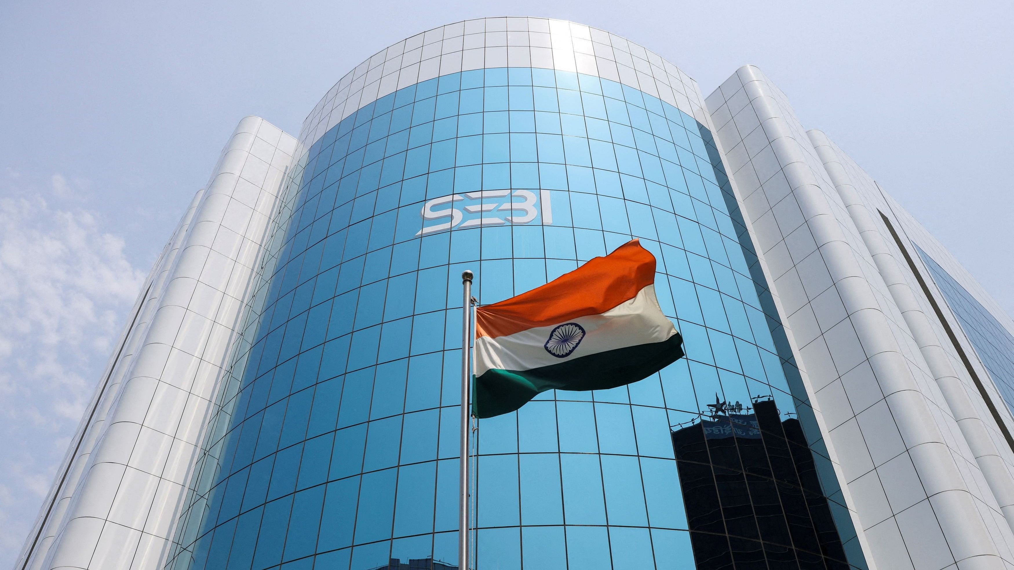 <div class="paragraphs"><p>The Indian flag flies in front of the new logo of the Securities and Exchange Board of India (SEBI) at its headquarters in Mumbai</p></div>